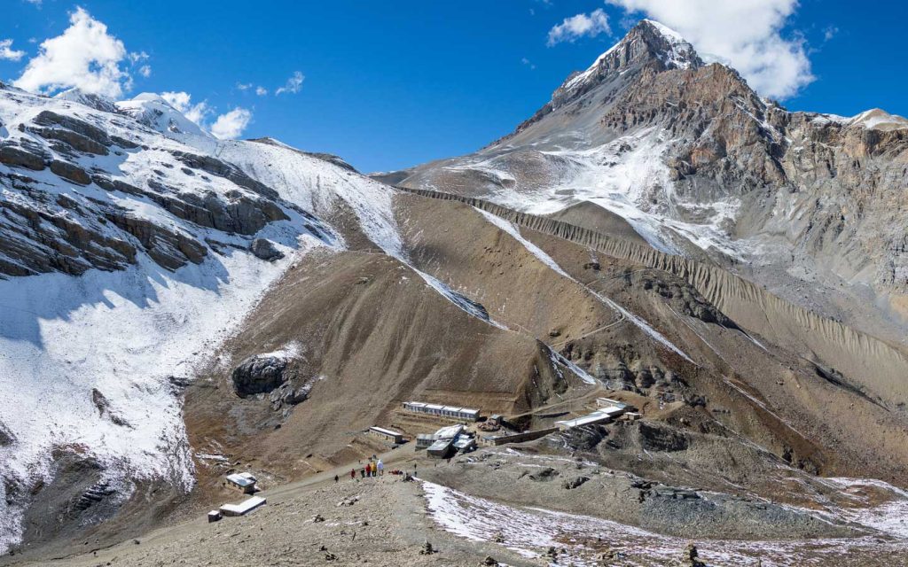 Thorong La Pass trail with dry high-altitude terrain and snow-covered peaks during the autumn trekking season in Nepal