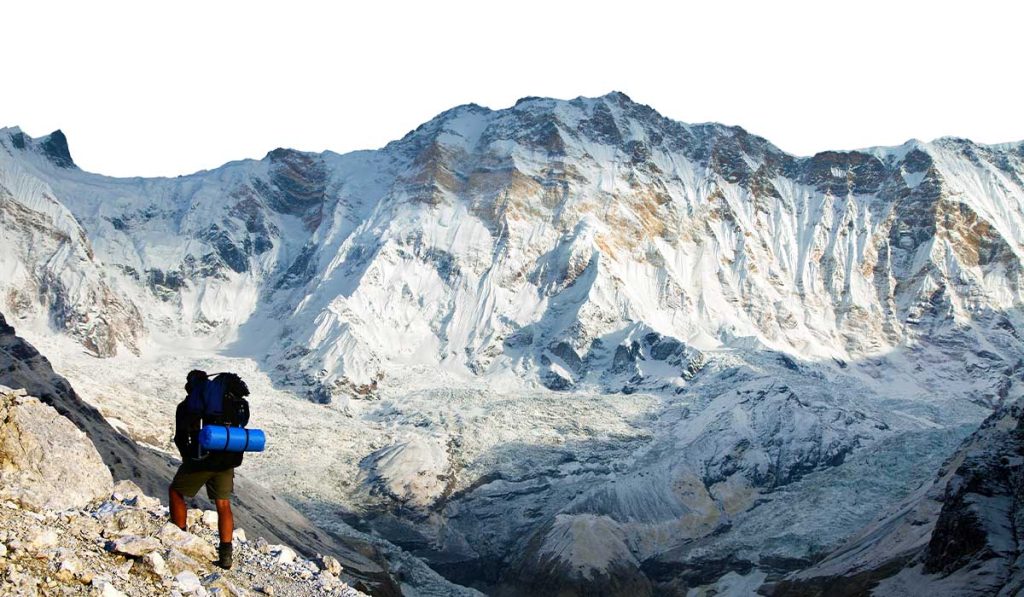 A trekker overlooking snow-covered mountains near Thorong La Pass during winter on the Annapurna Circuit.