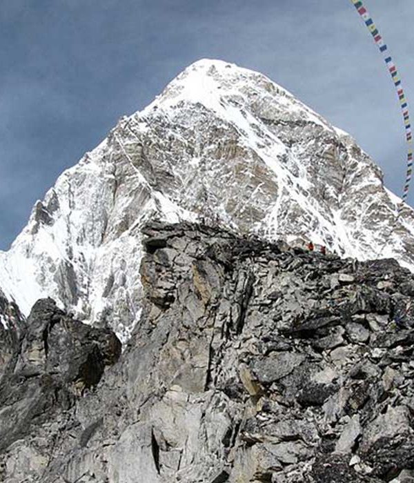 Colorful prayer flags fluttering over the rocky viewpoint of Kala Patthar, a major highlight on the Everest Base Camp Trek without flight.
